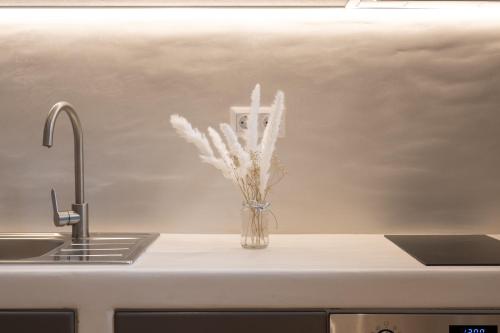 a vase of white flowers sitting on a kitchen counter at Little Yard Studios & Apartments #4 in Naxos Chora