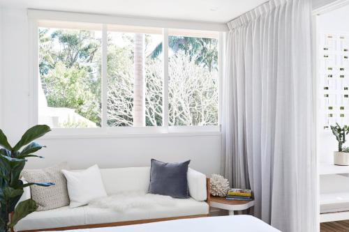 ein Wohnzimmer mit Sofa und großem Fenster in der Unterkunft Bask & Stow I Luxe Guesthouse in Byron Bay