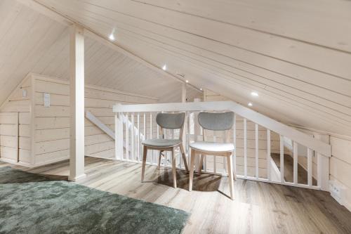 two chairs in a attic room with a staircase at Villa Mokum by PolarVillas in Kittilä