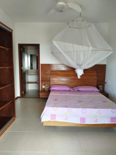 a bedroom with a bed with a mosquito net at Varanda das Palmeiras in Cairu