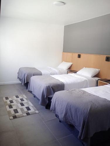 a row of four beds in a room at Hotel Manquehue in Esquel