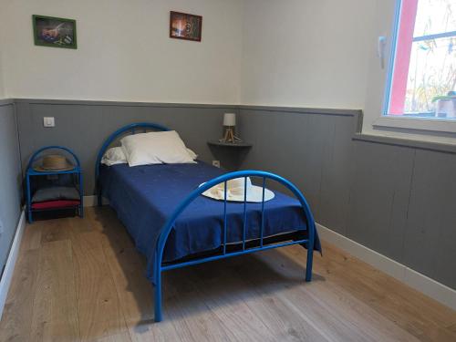 a bedroom with a blue bed and a window at Maison de pêcheur in Marseillan