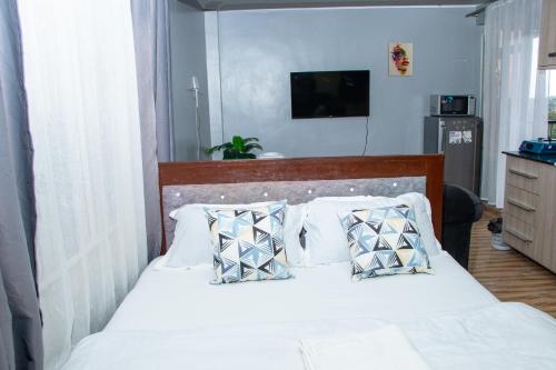 a bedroom with a bed with white sheets and pillows at Patrach Homes in Wote
