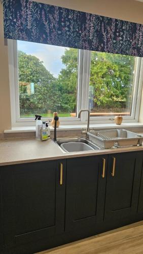 a kitchen counter with a sink and a window at Cosy wee cottage -modern, open plan, parking, EV in Glencaple