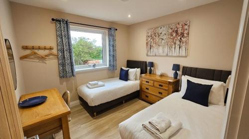 a bedroom with two beds and a window at Cosy wee cottage -modern, open plan, parking, EV in Glencaple