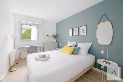 ein Schlafzimmer mit einem großen weißen Bett und einer blauen Wand in der Unterkunft Le Mirabeau in Rennes