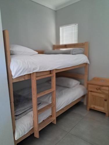 a room with two bunk beds with white sheets at Silwerrand in Beaufort West
