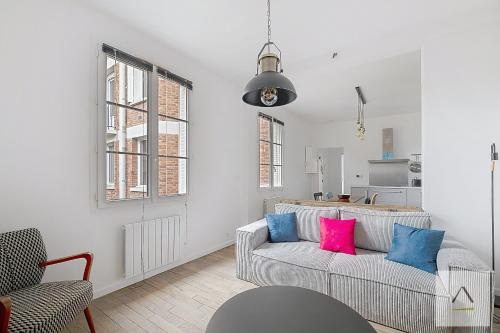 un salon avec un canapé gris et des coussins roses et bleus dans l'établissement L'Odorico, à Rennes