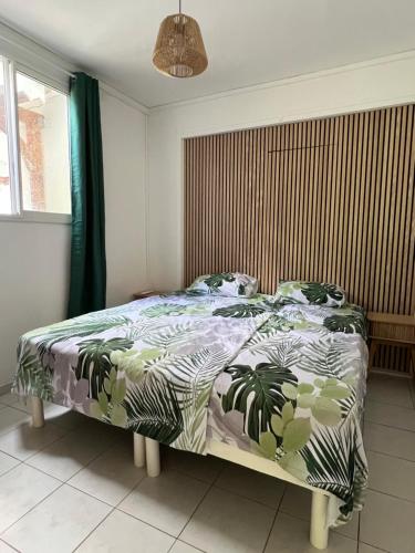 a bedroom with a bed with a green and white comforter at La Maison du Bonheur in Pointe-Noire