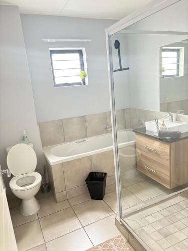 a bathroom with a tub and a toilet and a sink at Monochrome View in Nelspruit