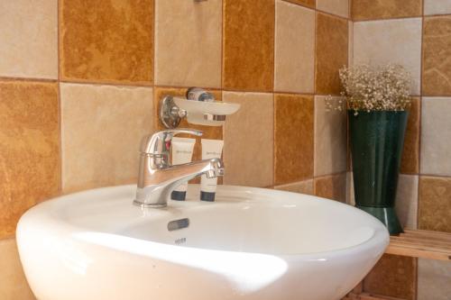 a bathroom sink with a faucet and a vase at Little Yard Studios & Apartments #6 in Naxos Chora