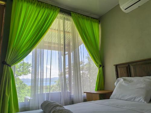 a bedroom with green curtains and a large window at Papaturro House in La Cruz