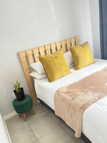 a bedroom with a bed with yellow pillows and a green stool at Monochrome View in Nelspruit