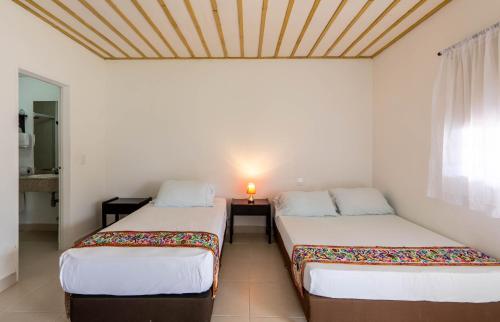 two beds in a white room with a window at Hotel campestre La Floresta in Armenia