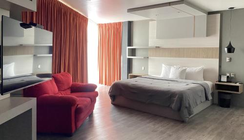 a bedroom with a bed and a red chair at ESDUMA HK HOTEL Pachuca in Pachuca de Soto