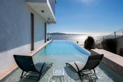 a swimming pool with two chairs and the beach at Modern Villa with Sea & River View Pool and Gym. in Lisbon