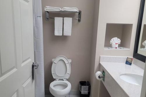 a bathroom with a toilet and a sink and towels at Baymont by Wyndham Houston Brookhollow in Houston