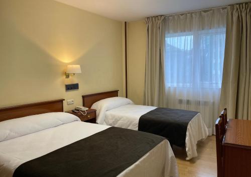 a hotel room with two beds and a window at Pensión Capital de Galicia in Santiago de Compostela