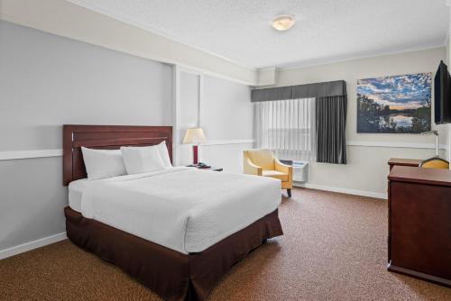 ein Hotelzimmer mit einem Bett und einem Stuhl in der Unterkunft Elk Island Studios - Lamont in Lamont