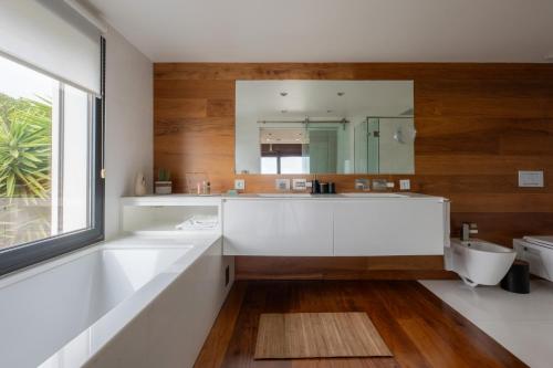 a bathroom with a large white tub and a mirror at Modern Villa with Sea & River View Pool and Gym. in Lisbon