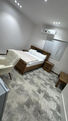 a white bedroom with a bed and a chair at ملاذ العلا in Al-ʿUla