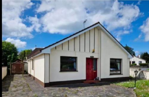 a small white house with a red door at Peggy's Place in Swinford