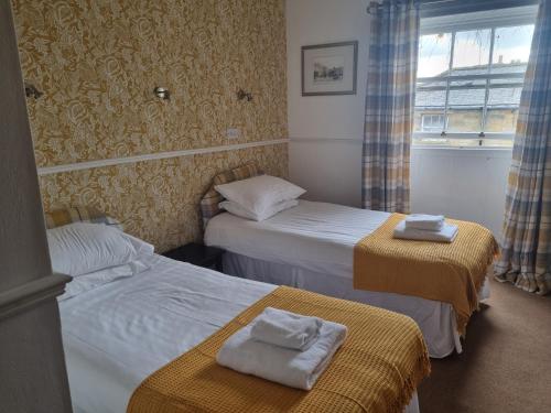 two beds in a hotel room with towels on them at Blue Bell Hotel in Belford