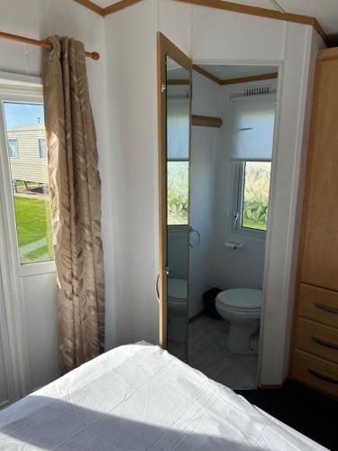 a bedroom with a bed and a bathroom with a toilet at 6 berth Ingoldmells The Grange With Ramp in Ingoldmells
