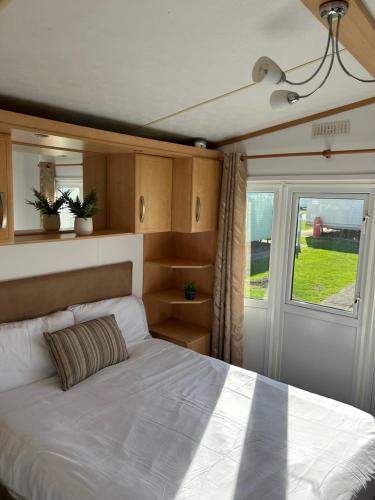 a bedroom with a white bed and a window at 6 berth Ingoldmells The Grange With Ramp in Ingoldmells
