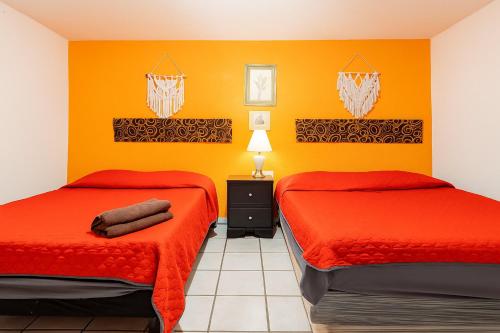 two beds in a room with orange walls at Hotel Fundidora - Regiotitlan in Monterrey