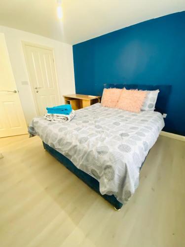 a bedroom with a bed with a blue wall at Stay with H&S in Kirk Sandall