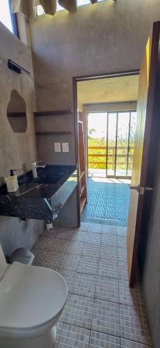 ein Badezimmer mit Toilette und Blick auf eine Tür in der Unterkunft Parcela in Mazunte