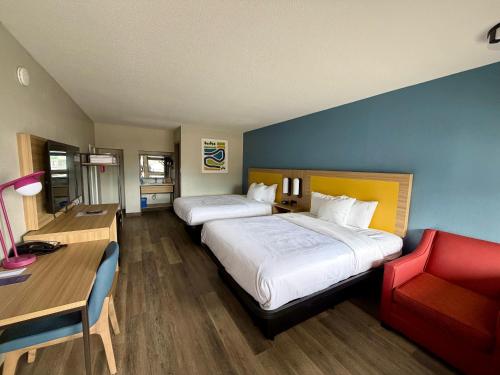a hotel room with two beds and a red chair at Park Inn by Radisson, Weldon - Roanoke Rapids in Weldon