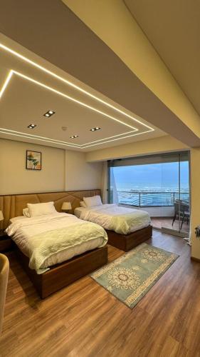 a bedroom with two beds and a large window at Sheraton Palace Sea View in Alexandria