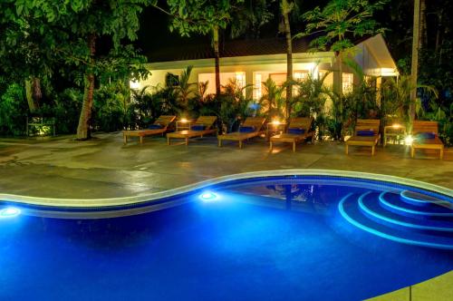 - une piscine de nuit avec des chaises et des tables dans l'établissement Moana Surf Resort, à Nosara