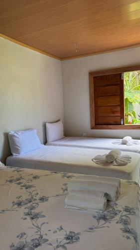two beds in a room with a window at Bangalô em uma área próxima a praia e centro in Porto Seguro