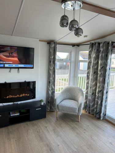 a living room with a chair and a flat screen tv at 6 berth Ingoldmells The Grange With Ramp in Ingoldmells
