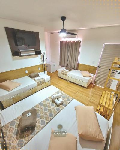 a living room with two beds and a flat screen tv at Pousada Akuto's in Aparecida