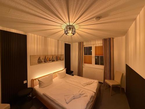 a bedroom with a white bed and a chandelier at Störtebekers Kuschelnest -265 in Sagard