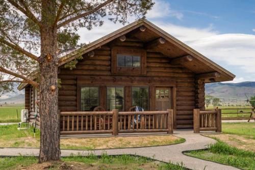 a log cabin with a porch and a tree at Copper Rose Ranch in Livingston