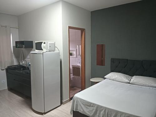 a bedroom with a bed and a refrigerator and a bathroom at Kitnets bem localizada, próx ao autódromo! in Londrina