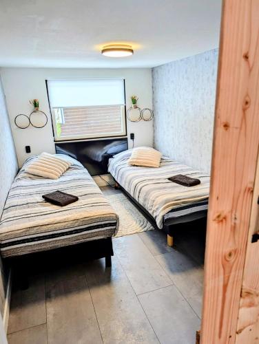 two twin beds in a room with a window at Chalet Timber -close to the woods in Anloo