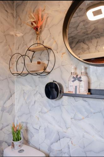a bathroom with a mirror and a white marble wall at Chalet Timber -close to the woods in Anloo