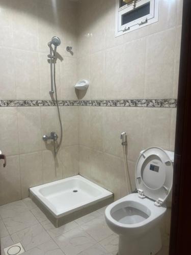 a bathroom with a shower and a toilet with the seat up at doge villa 7 in Dubai