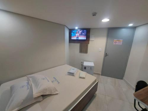a bedroom with a bed with a tv on the wall at Hotel Estação - Osasco in Osasco