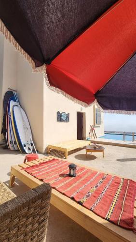 a room with a table with a red umbrella at La Cabane Surf Lodge in Agadir