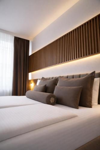 una camera da letto con un grande letto bianco con cuscini marroni di Hotel Bayer's a Monaco