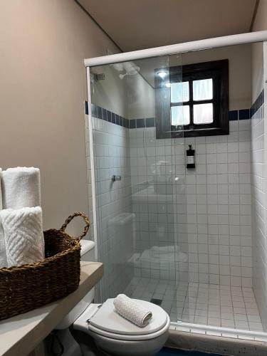 a bathroom with a toilet and a glass shower at Casa 1915 Pousada in Morretes