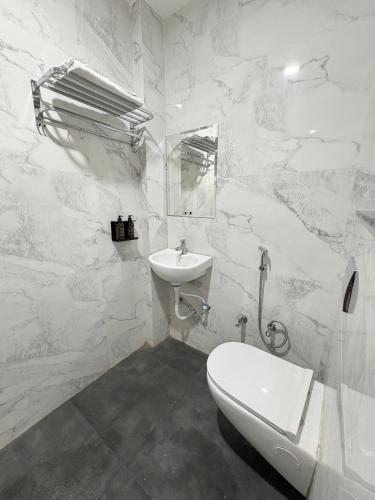 a white bathroom with a sink and a toilet at Hotel Synergy Stays in Indore