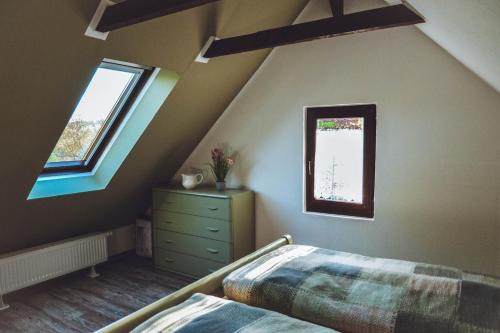 a attic bedroom with a bed and a dresser and two windows at Ferienhaus Vogtland mit Sauna und Hot Tub in Weischlitz
